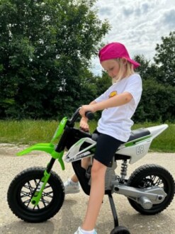 Meisje op een mini-motorfiets met roze pet