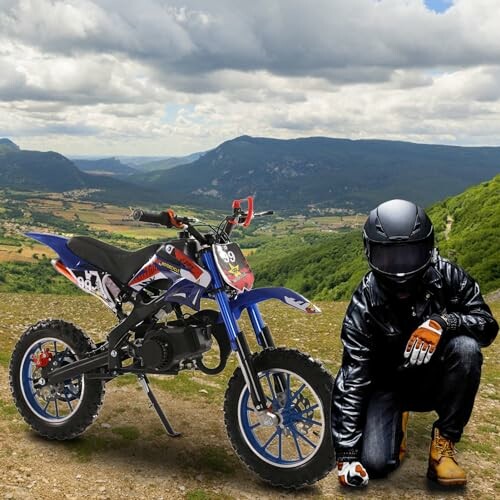 Motorrijder poseert naast crossmotor in berglandschap.